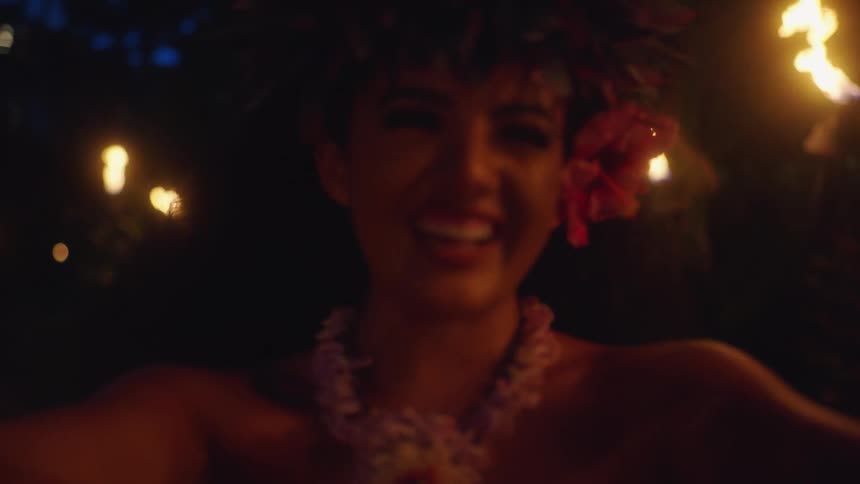 Girl gives the cameraman a lei garland or wreath at night