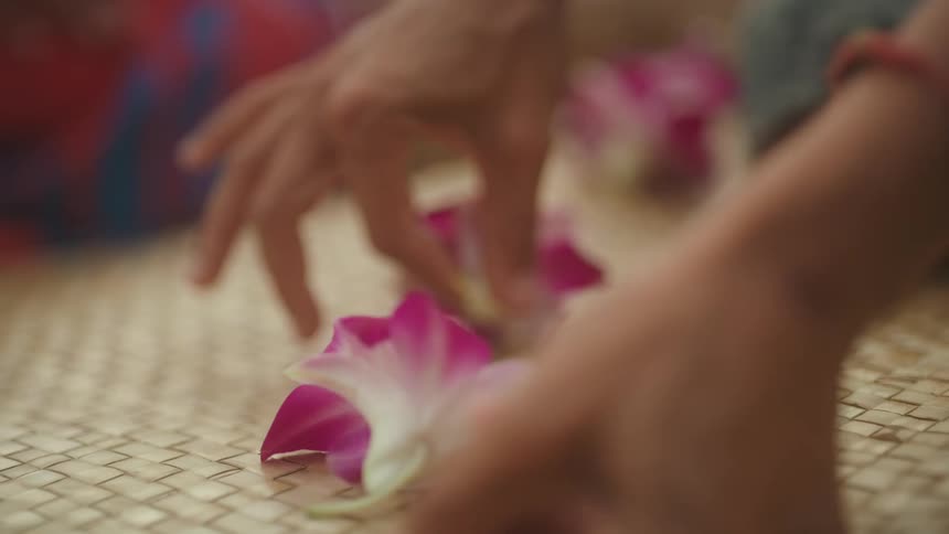 Hawaiian women thread flowers into lei