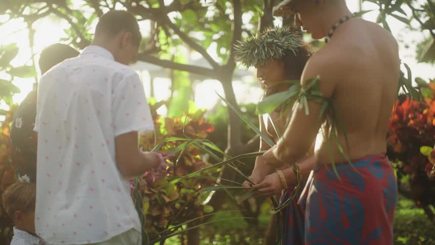 A group of people standing together outdoors braiding leaves