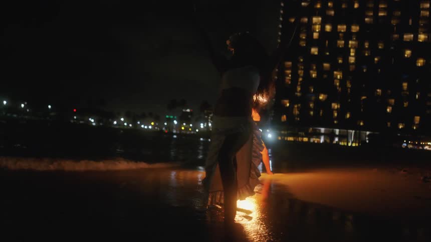 Polynesian dance poses on beach as fire dancer performs