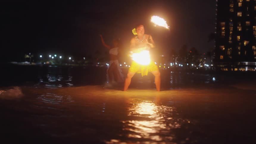Hawaiian fire dancer performing on the beach at night