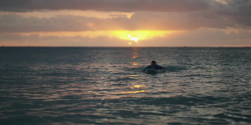 A man is paddling on his surfboard in the water