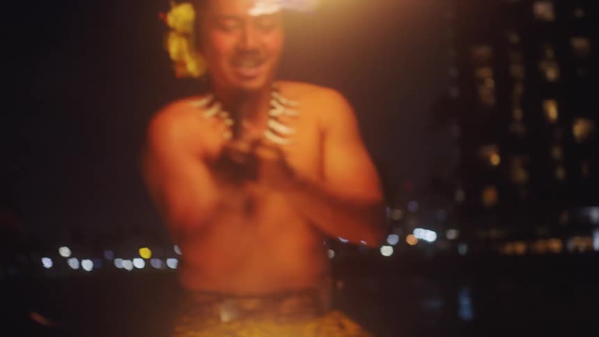 A man fire dancing with a woman posing in the background