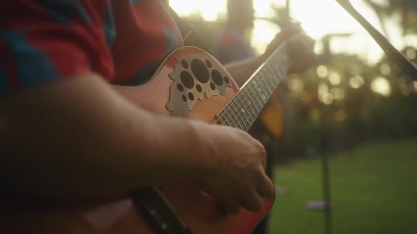 A band performs together outside with guitars