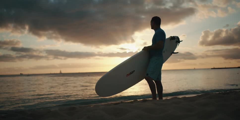 A surfer looks out to sea holding a surfboard