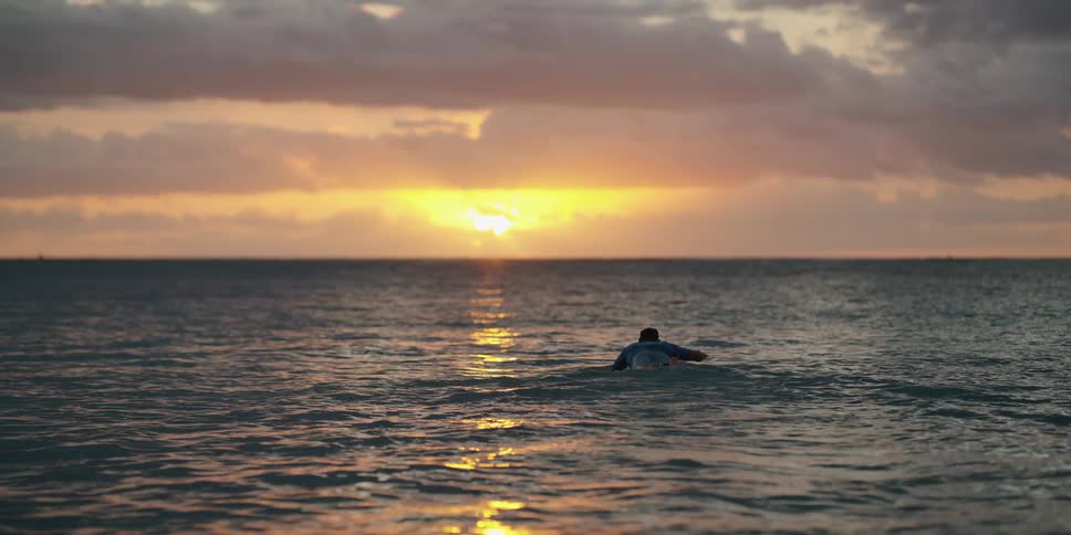 A man paddles his surfboard out