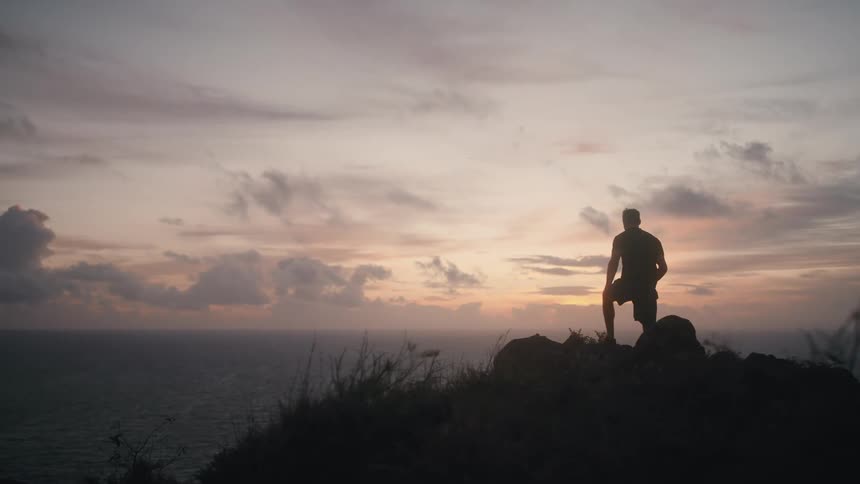 Man quickly walks to the edge of the cliff at sunset