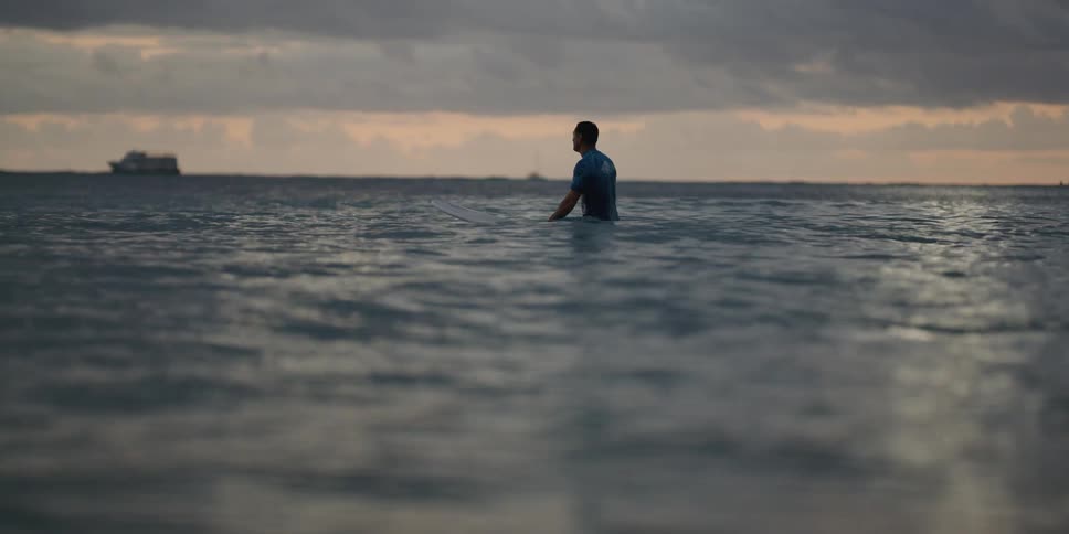 A man is sitting on a surfboard in the middle of the ocean
