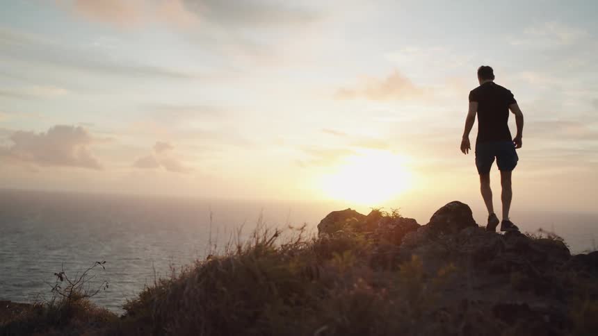 A man climbs up running on the cliff near the ocean