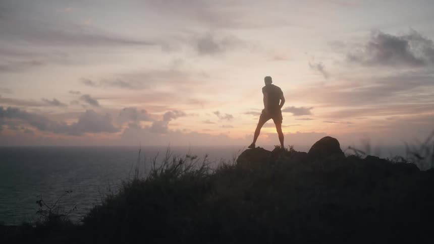 A man jogs up and over the at sunrise
