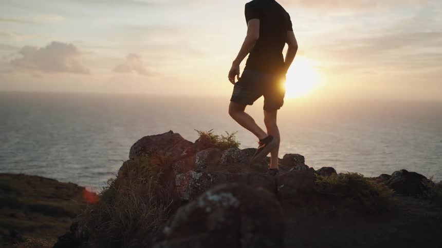 A man runs up to the edge of a cliff near the ocean