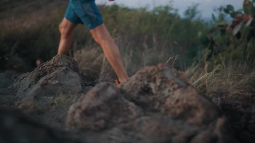Man walks uphill at sunset on a windy day