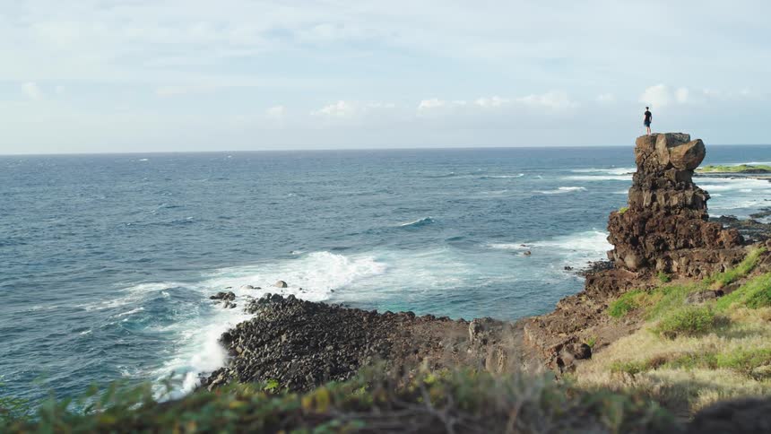 Man stands over rock in the coast in front of the sea