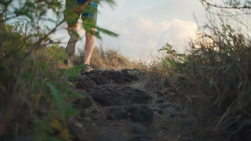 A person runs through a grassy area with rocks