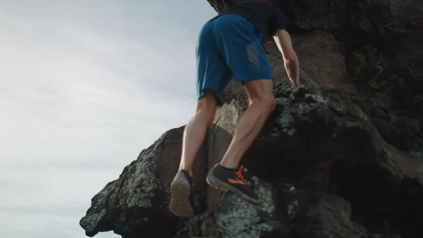 Man climbs up the rocks near the ocean