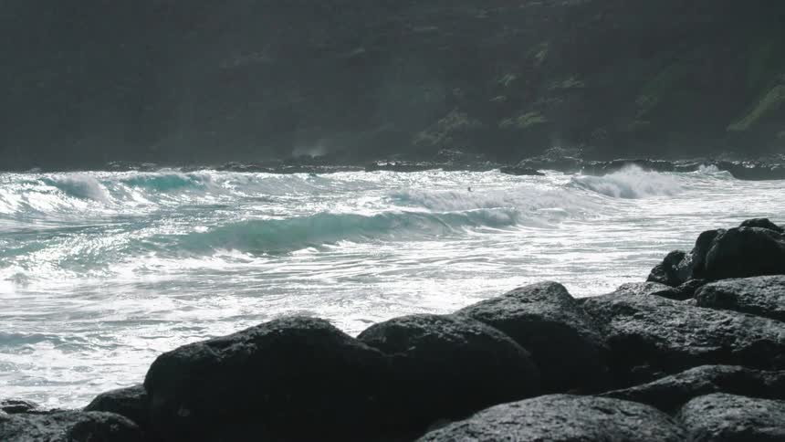 Ocean waves crash against the rocky shore during daylight