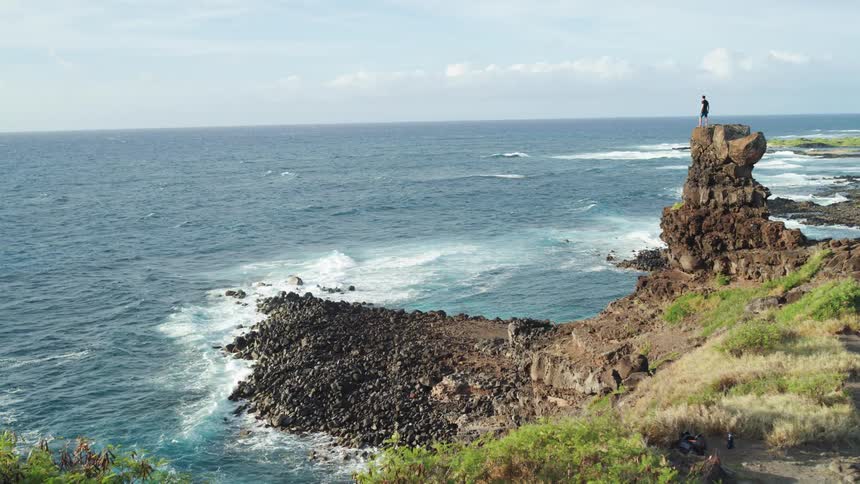 Man stands on the steep rock by the coast