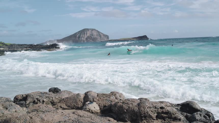 Ocean waves crash against the beach while people swim