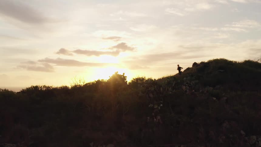 A jogger running down a hill near the ocean at sunrise