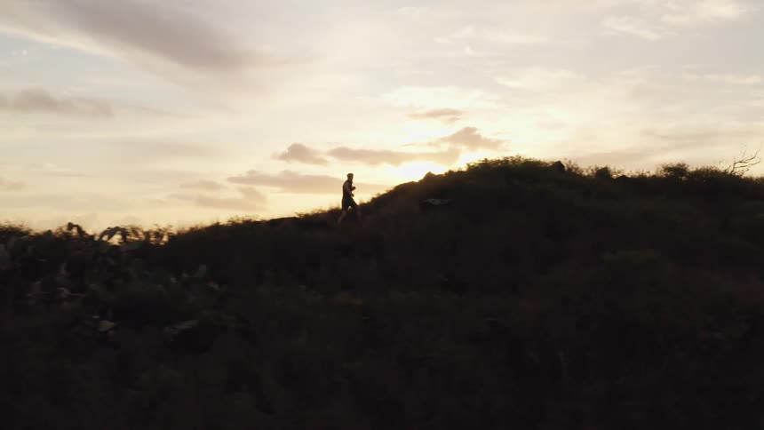 A jogger running up a hill at sunrise