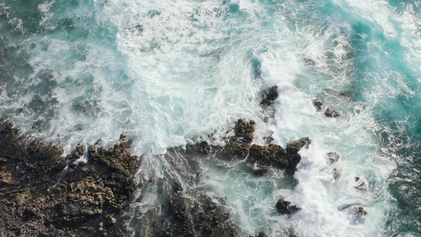 Ocean waves crash against rocks during daylight