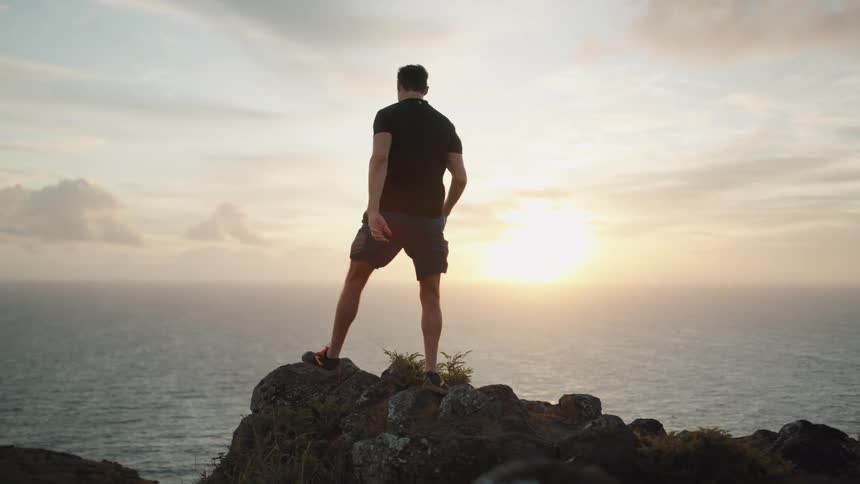 A man runs up some rocks and looks at the water below