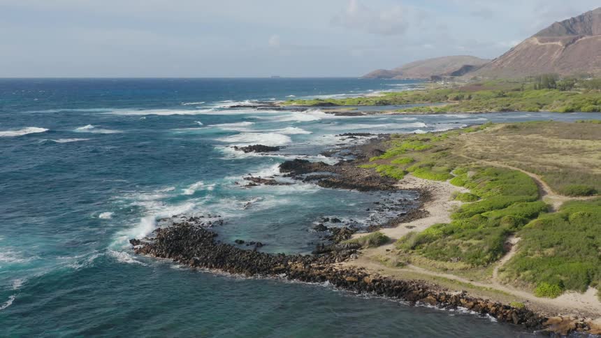 Aerial view of ocean waves crashing against the rocky shore during daylight