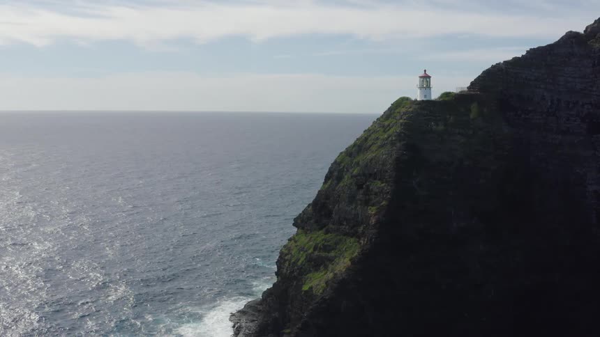 Lighthouse on the face of a cliff in front of the ocean
