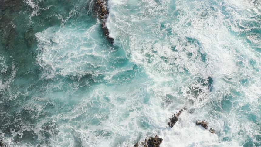 Waves crashing on beach rocks at day