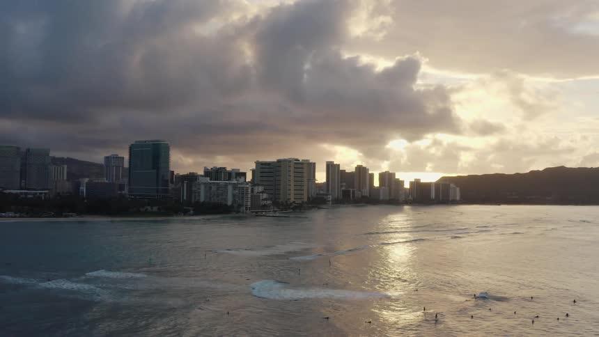 Cityscape of the city with tall buildings at sunset next to the ocean