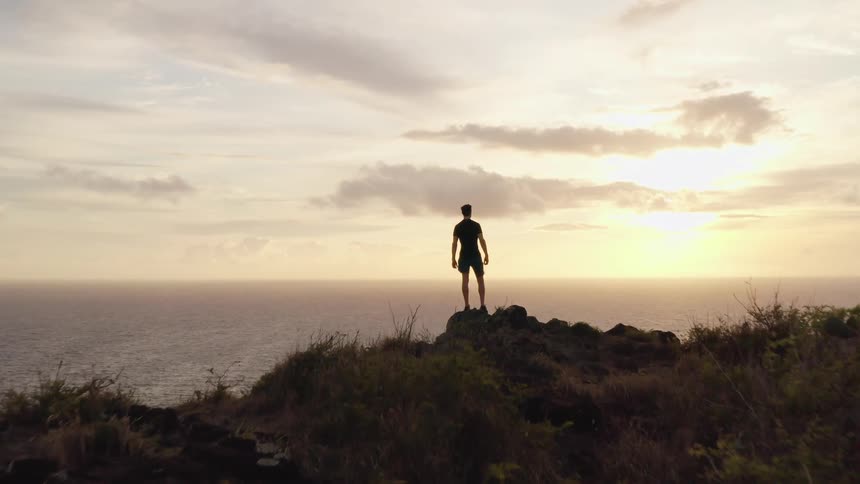 A man stands on the hill by the shore