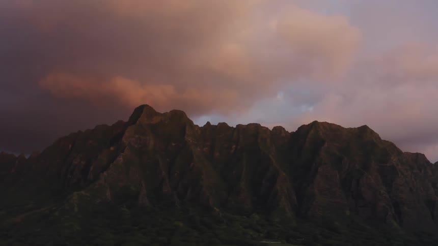A jagged rocky ridge with clouds above at sunset