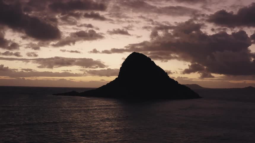 A small island with a hill on it in the middle of the ocean