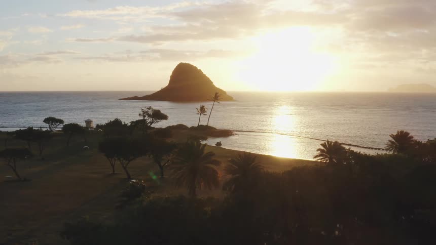 Coastline of mainland and silhouette of island in ocean at sunset