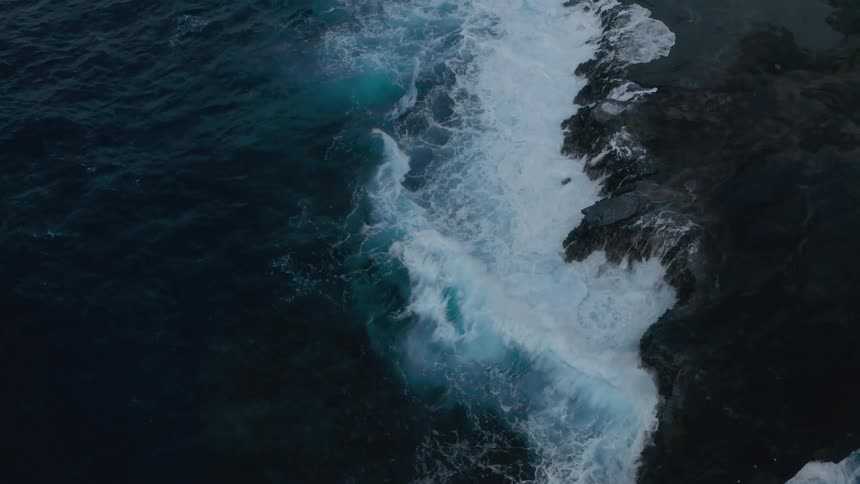 Birds eye view of waves crashing in to a cliff