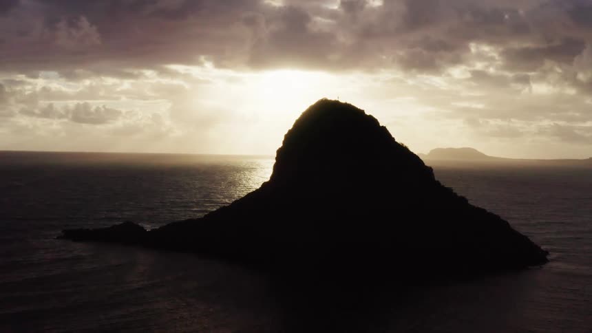 Small rocky island silhouetted against sunset