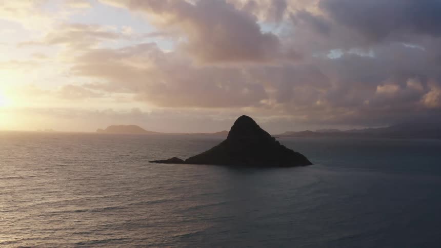 A small island with the sky and the clouds in the background