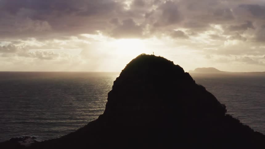 Man climbs small island on the sea at sunset