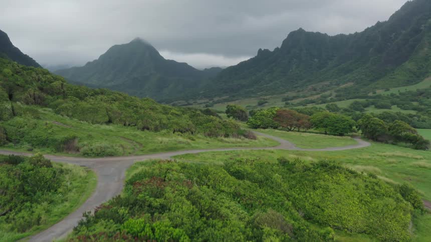 Road running through a verdant valley between mountain ridges on a cloudy day