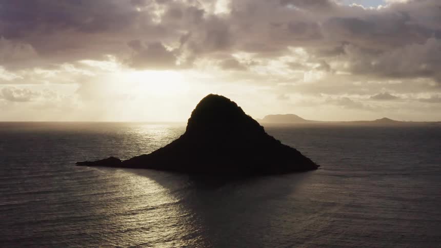 A small cone shaped island on a cloudy day