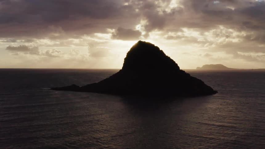 Aerial of large rock formation in the ocean under stormy sky