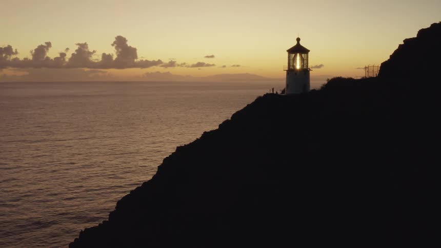 A light house sits on a hill above the ocean