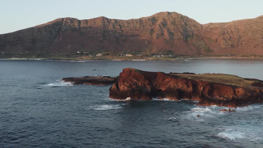 A neighborhood sits below a mountain range next to the ocean