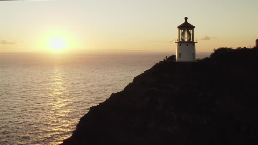 Lighthouse on high seaside cliff at sunset