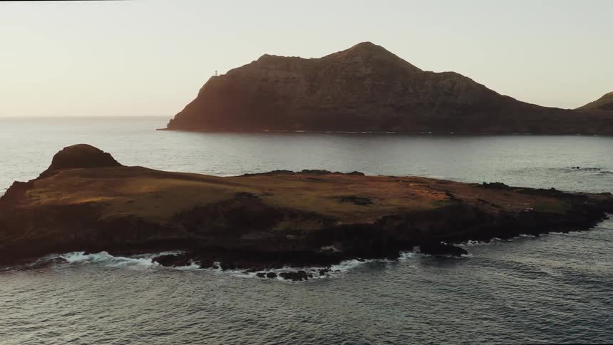 A small rocky island with another land in the background