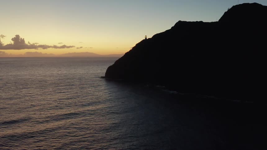 Lighthouse on a cliff near the ocean at sunset
