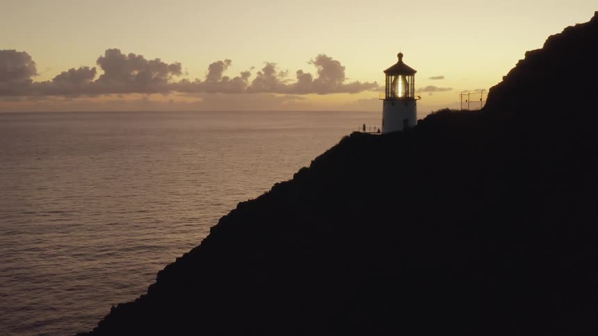 A lighthouse on the rocky shore with the ocean and sky in the background