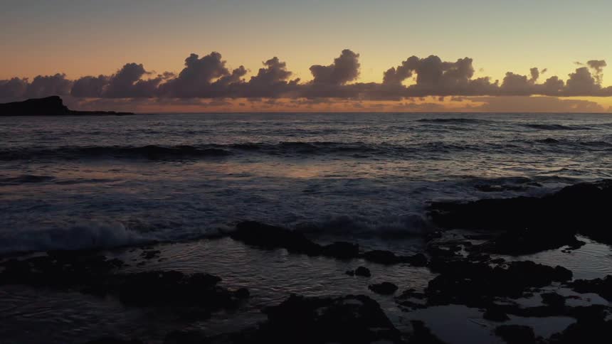 Waves crash onto the shore at sunset