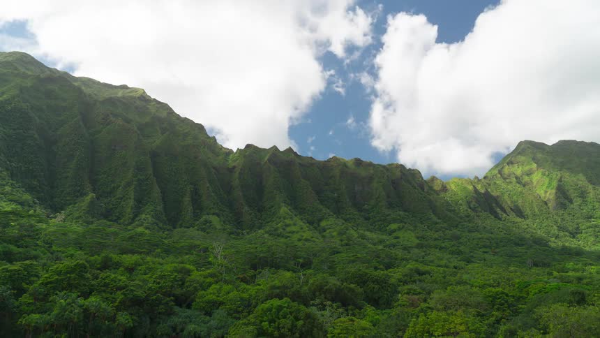 Time lapse of clouds over tropical vegetation and mountain range