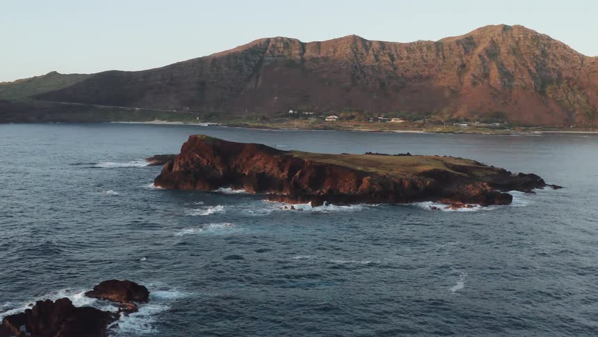 Small island in front of coastal small town by the mountains